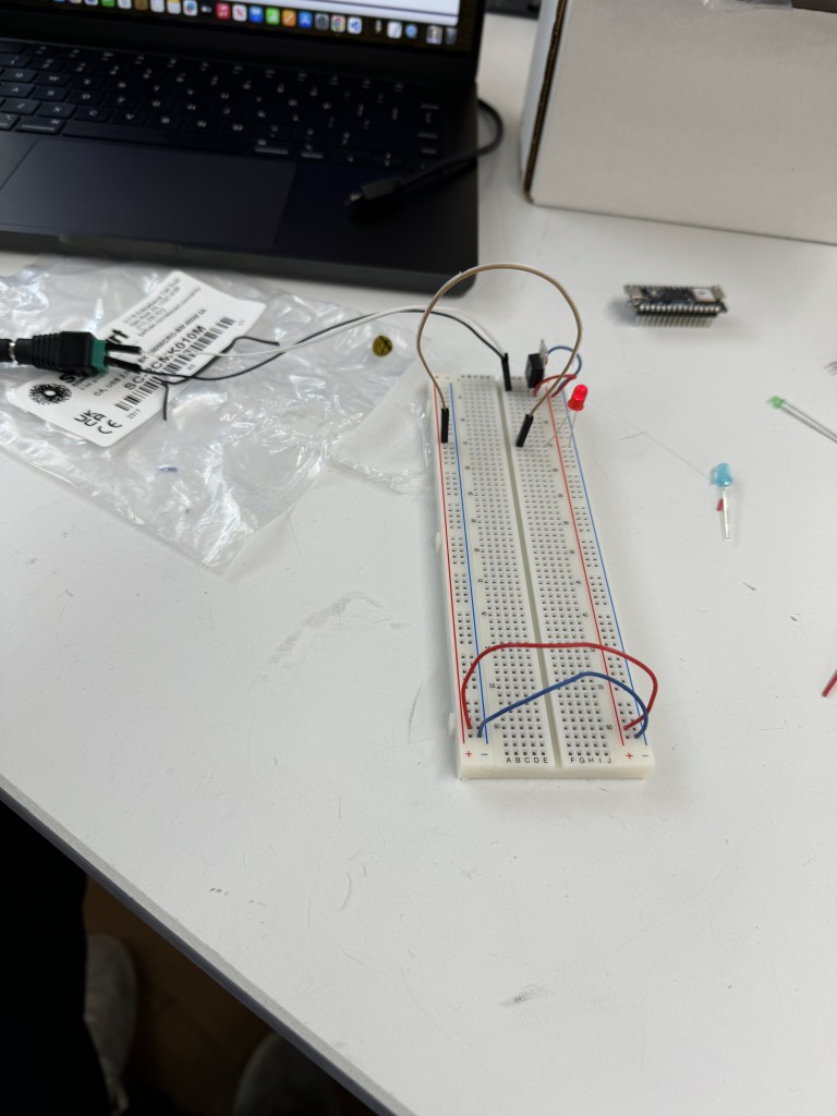 Eureka! A working breadboard with an unseen plugged in AC Adapter plugged into a DC jack, which then connects to the breadboard and voltage regulator. Wires arranged properly to an red LED light, that is on and bright!